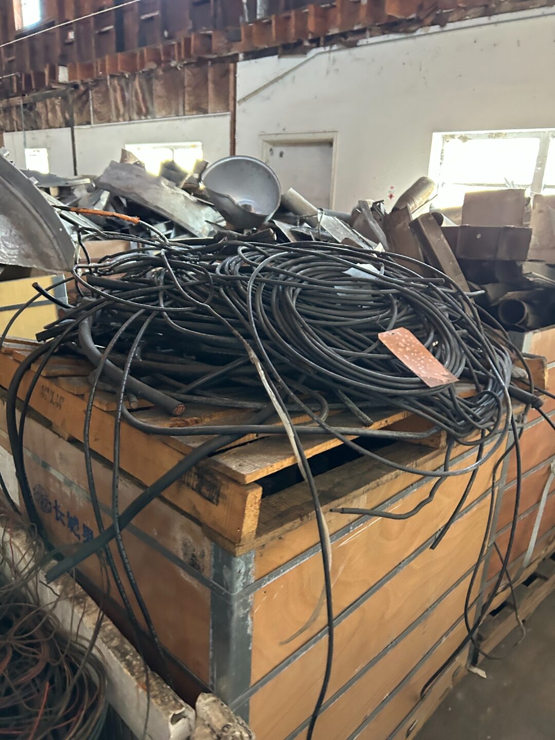 Tangled black and green wire piled in a crate on a pallet